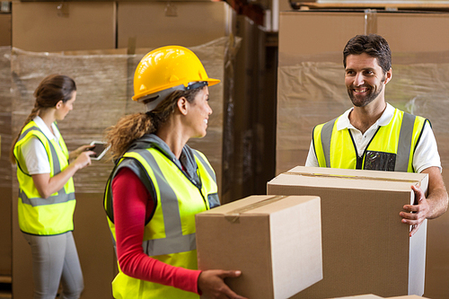 Portrait of workers are holding cardboard boxes and looking each other in a warehouse