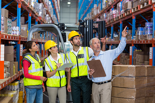 Manager and workers are looking shelves and pointing in a warehouse