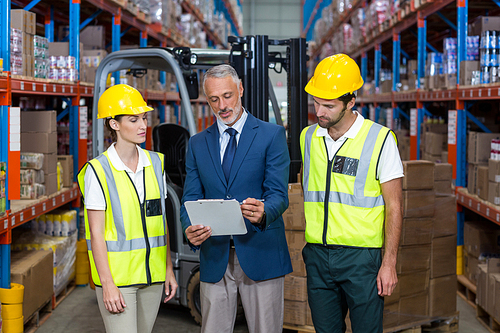 Manager showing tablet to workers in a warehouse