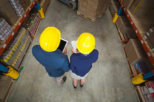 High angle view of managers with hard hat holding tablet and clipboard in a warehouse