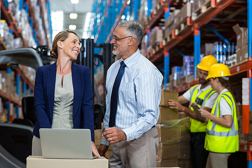 Portrait of happy managers are looking each other and smiling in warehouse