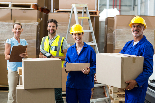 Smiling workers carrying boxes in warehouse