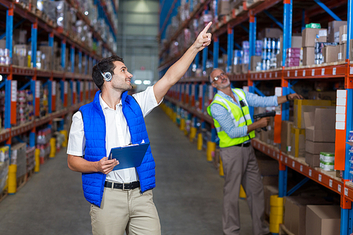 Workers showing to his  colleague something up in warehouse