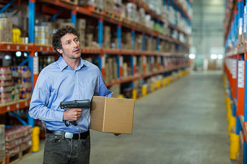 Standing worker holding a box in warehouse