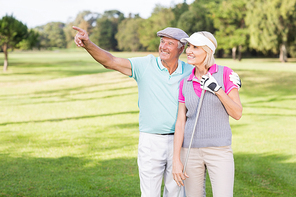 Smiling golfer man pointing while standing by woman