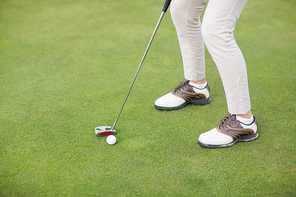 Low section of woman playing golf while standing on field