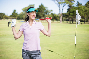 Happy woman carrying golf club while standing on field