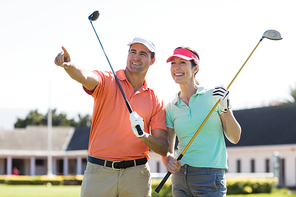 Golfer man pointing while standing by woman on field