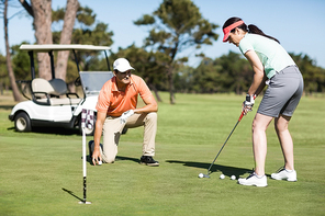 Woman playing golf while standing by man on field