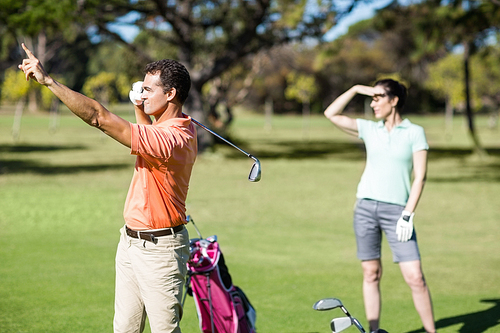 Golfer pointing while standing by woman at golf course