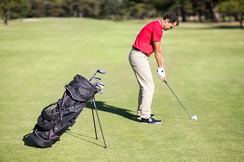 Full length side view of man playing golf while standing on field