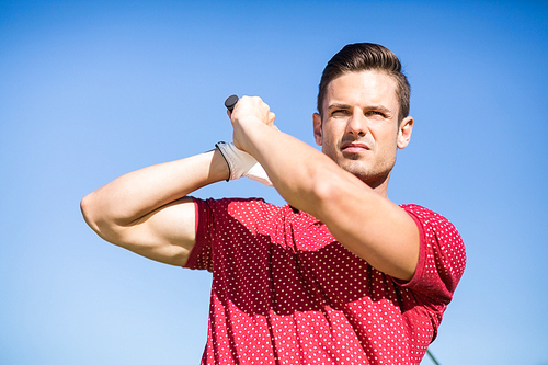 Low angle view of golfer man taking shot while standing against clear sky