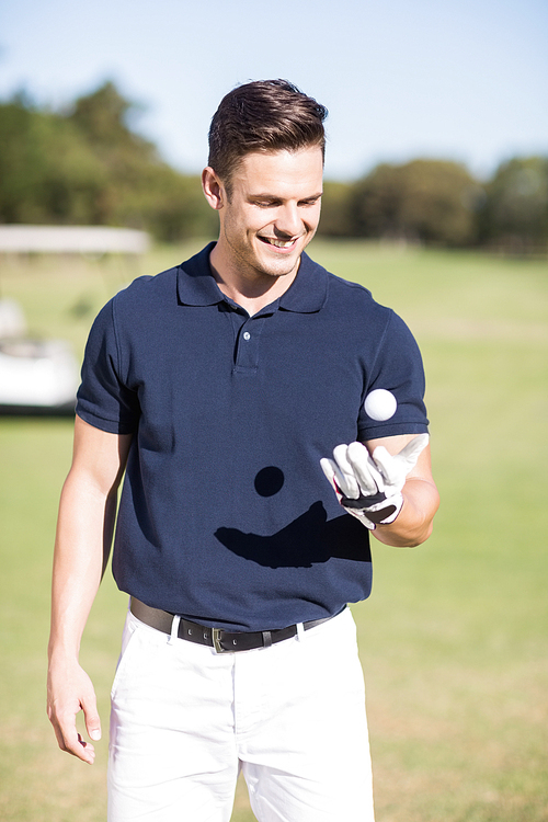 Cheerful young man with golf ball while standing on field