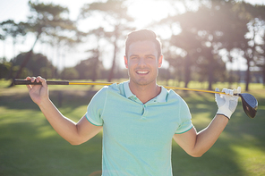 Portrait of smart man carrying golf club while standing on field