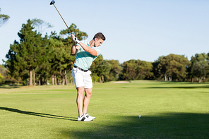 Concentrated golfer man taking shot while standing on field