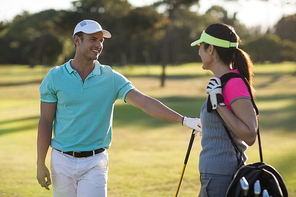Happy golf player couple standing on field