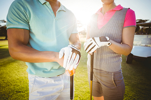 Midsection of golfer couple standing on field