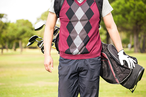 Midsection of man wearing golf bag while standing on field