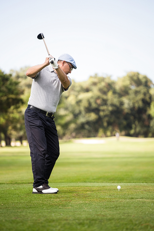 Profile view of man playing golf while standing on field