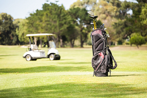 Filled golf bag and golf buggy on field