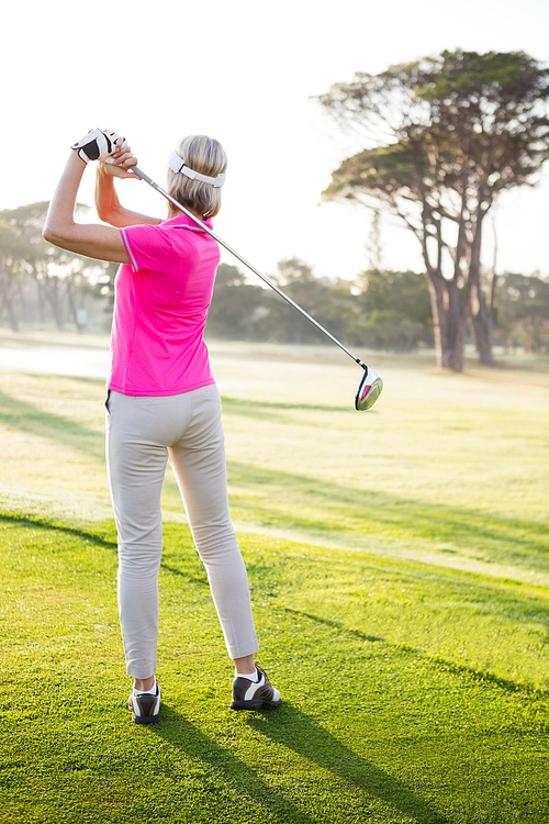 Rear view of sportswoman playing golf on field
