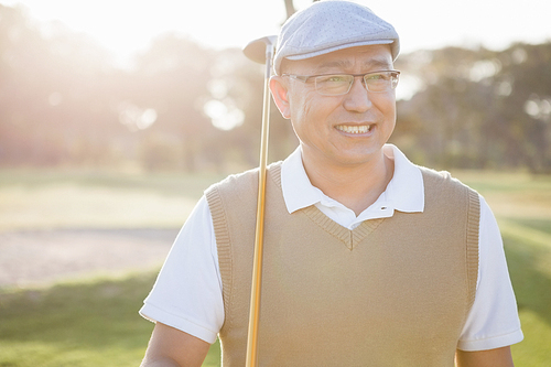 Sportsman holding his golf club and looking away on a field