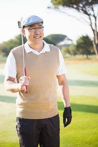 Portrait of sportsman holding his golf club and looking away on a field