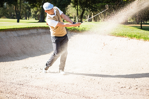 Side view of sportsman playing golf on a sandbox