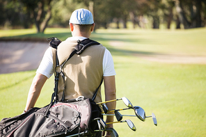 Rear view of sportsman holding a golf bag on a field