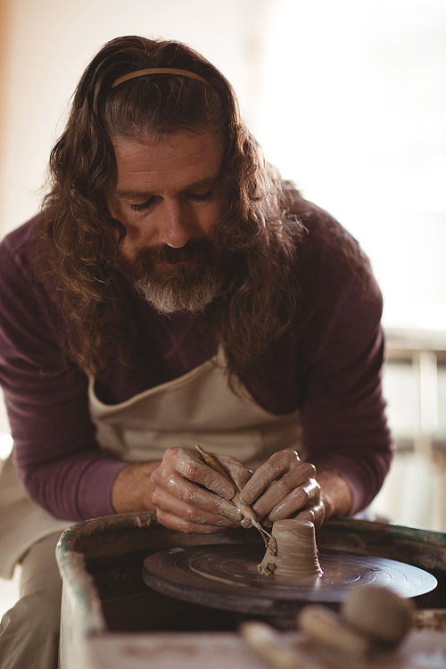 Male potter working on bowl in pottery workshop