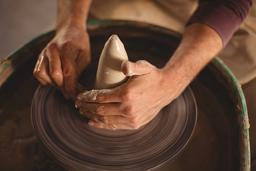 Close-up of male potter making pot in pottery workshop