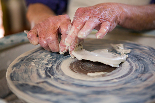 Close-up of potter removing clay from pottery wheel in pottery workshop