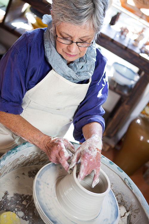 Attentive female potter making pot in pottery workshop