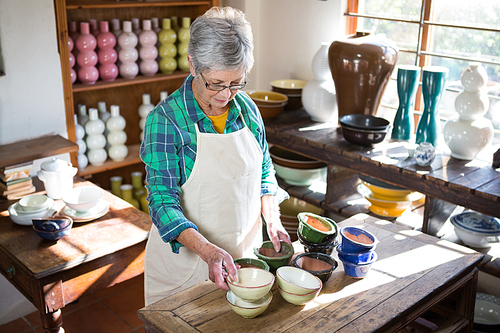 Female potter arranging bowl on worktop in pottery workshop