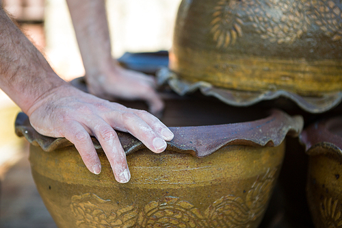 Close-up of male potter checking pot in pottery workshop
