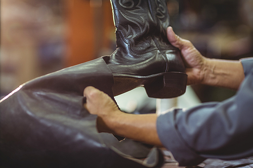 Cobbler making leather boots in workshop