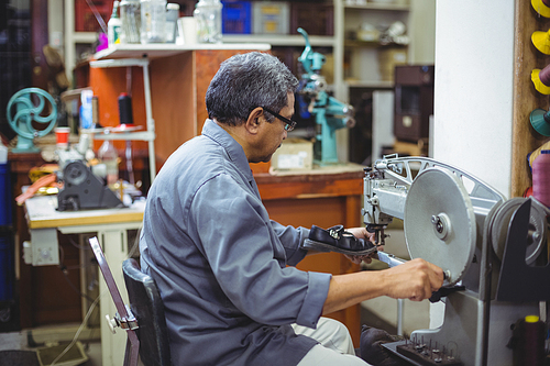 Shoemaker using sewing machine in workshop