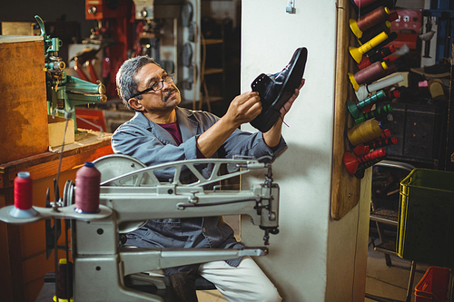 Shoemaker examining a shoe in workshop