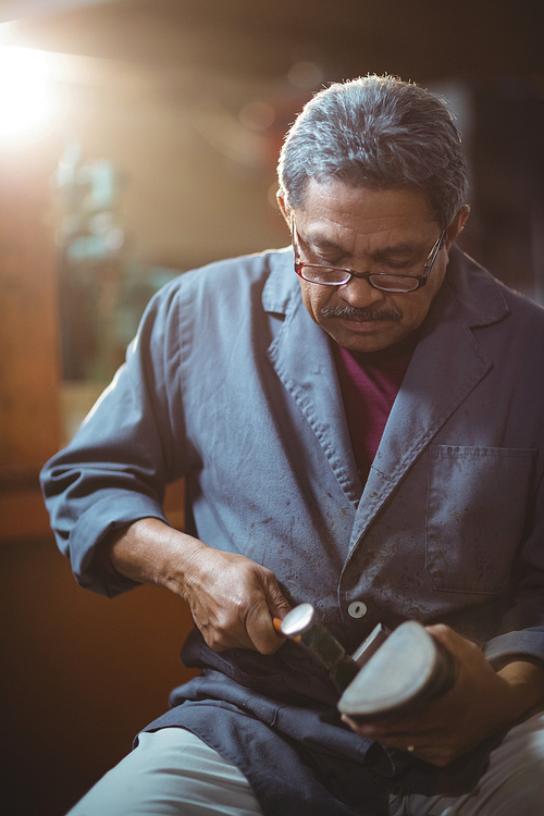 Shoemaker making a shoe with hammer in workshop