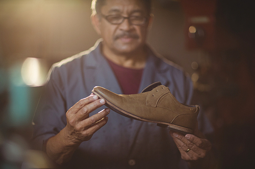 Shoemaker examining a shoe in workshop