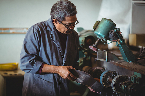 Shoemaker polishing a shoe with machine in workshop