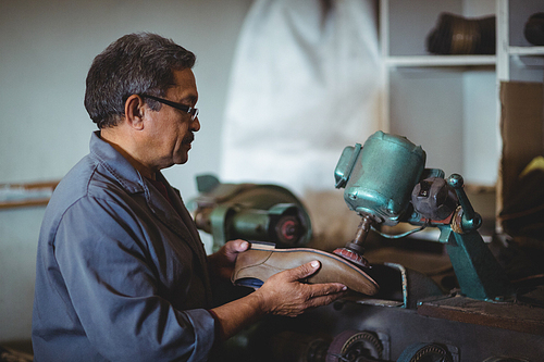 Shoemaker polishing a shoe with machine in workshop