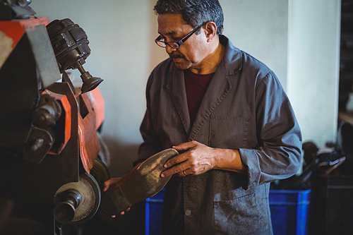 Shoemaker polishing a shoe with machine in workshop