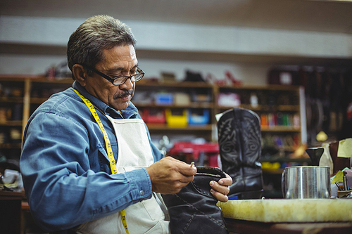 Shoemaker applying glue on shoe in workshop