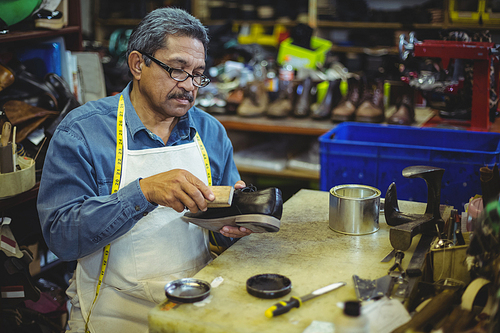 Shoemaker polishing a shoe in workshop