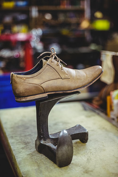 Leather shoe on shoe repair stand in workshop
