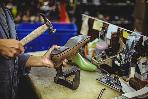 Shoemaker hammering on a shoe in workshop