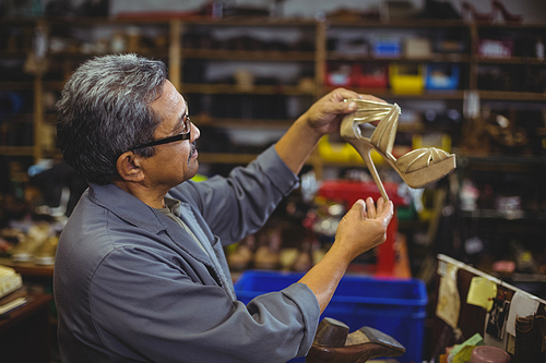 Shoemaker examining a high heel in workshop