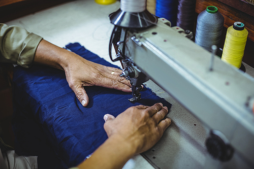 Shoemaker using sewing machine in workshop