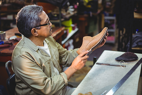 Shoemaker examining a shoe in workshop